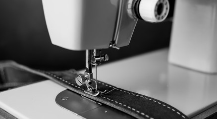 Background type of sewing machine, leather belt sewing process. Leather workshop.