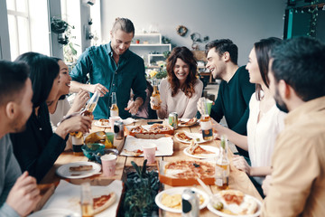 Real friendship. Group of young people in casual wear smiling while having a dinner party indoors
