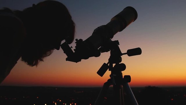 Girl looking through a telescope at the stars.