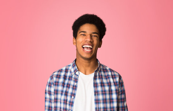 Excited guy laughing and looking at camera, pink background