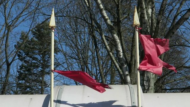 two torn red flags fluttering in the wind. flagpoles on the building