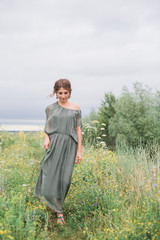 beautiful young girl in a summer dress in a field on a background of green grass