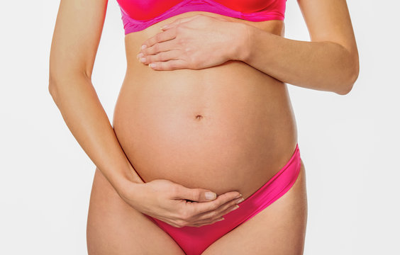 Pregant woman is holding belly with hands, on white background.