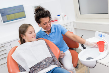 Zahnarztassistentin erklärt junger Patientin die Geräte in der Praxis