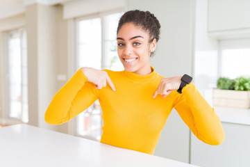 Beautiful young african american woman with afro hair looking confident with smile on face,...