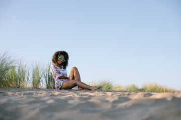 Young beautiful black woman relaxing at the beach on summer or spring vacation. 