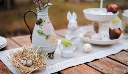 Served festive decorative table garden outdoors. Farm. Rustic style. Willow spring bloom. Flowers cookies glass jar. Easter