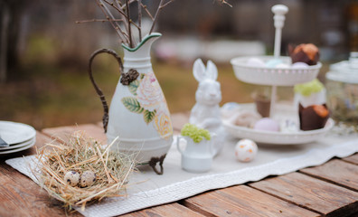Served festive decorative table garden outdoors. Farm. Rustic style. Willow spring bloom. Flowers cookies glass jar. Easter