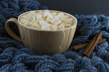 Nice Cup of coffee with marshmallow. Blue knitted background.