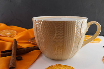 A Cup of coffee in a cozy style on a white background and an orange fabric. Slices of dried orange and persimmons.