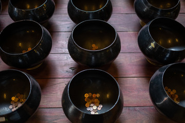 coins in the alms bowl at the Thai temple