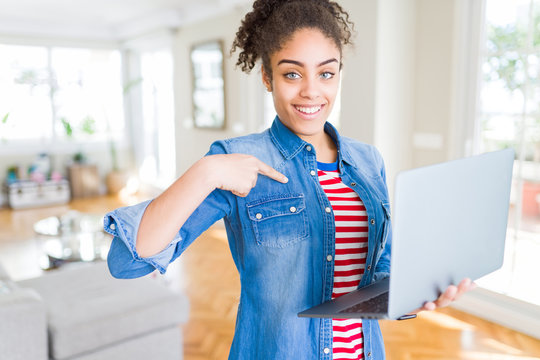 Young african american girl standing working using laptop with surprise face pointing finger to himself