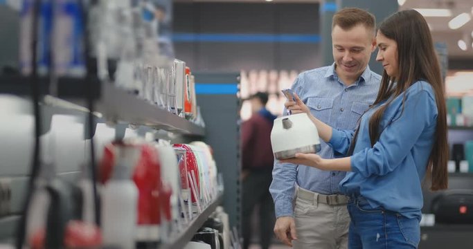 Young family chooses electric kettle for their new home in appliances store