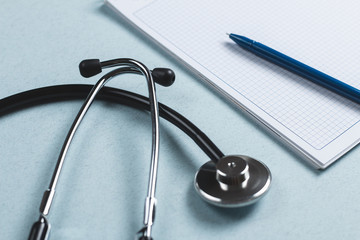 Stethoscope near an open, empty notebook and pen. Side view