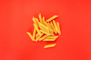 dry pasta penne Italian food red background.