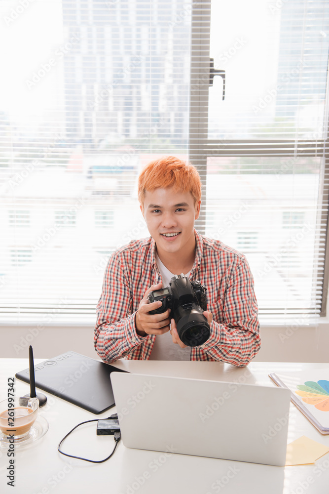 Fototapete smiling photo editor working on computer at desk with camera and graphics tablet