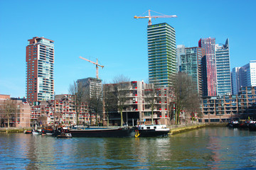 Obraz premium The modern and touristic port of Rotterdam on a sunny spring day. In the metropolis boats, ships and fishing boats wake up in the morning ready for work.