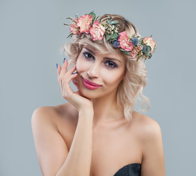 Spring portrait of cheerful woman in flowers crown. Beautiful model with short hair and makeup smiling