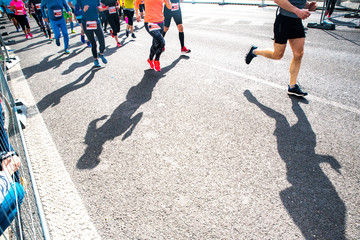 Crowd run in the city on the road. Group race, legs and shadows