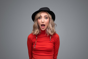 Astonished woman in hat looking at camera