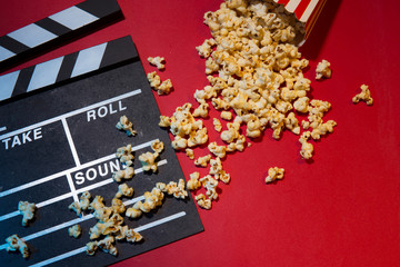Cinema concept. Clapperboard, ticket and popcorn on red background