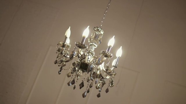 Beautiful chandelier, with transparent pendants and burning lamps