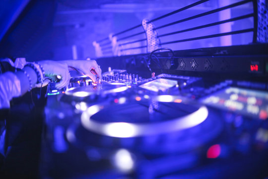 Detail of woman's hand playing with a mixer in a nightclub