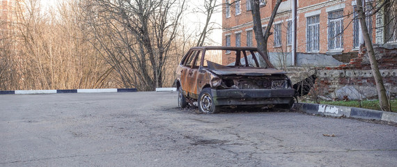 Abandoned burned passenger car near the apartment building. Russia.