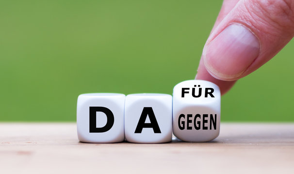Daf&uuml;r oder Dagegen? Hand dreht einen W&uuml;rfel und &auml;ndert den Ausdruck "dagegen" in "daf&uuml;r" (oder umgekehrt).