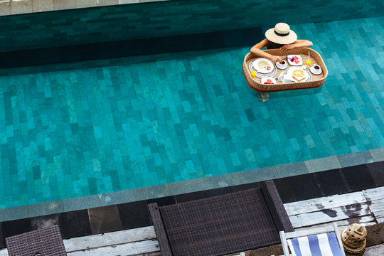 Girl eating floating breakfast in luxury hotel pool