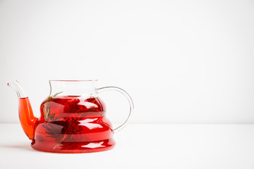 Hot raspberry beverage with rosemary in glass teapot. Selective focus. Shallow depth of field.