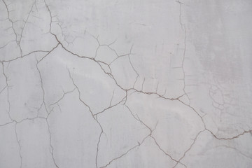 A crack in the concrete wall. Textured stone gray wall. Peeling paint on the cement surface.