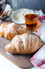Fresh croissant with tea for breakfast. Food photography background.
