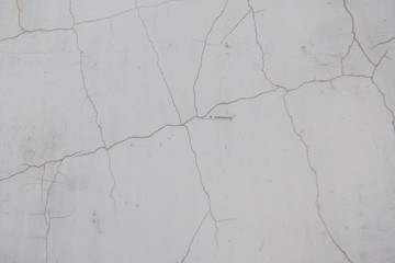 A crack in the concrete wall. Textured stone gray wall. Peeling paint on the cement surface.