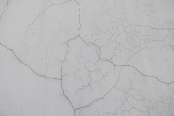 A crack in the concrete wall. Textured stone gray wall. Peeling paint on the cement surface.