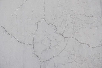 A crack in the concrete wall. Textured stone gray wall. Peeling paint on the cement surface.