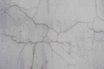 A crack in the concrete wall. Textured stone gray wall. Peeling paint on the cement surface.