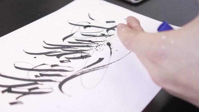 A contemporary artist makes calligraffiti on paper.