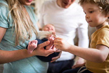 Midsection of parents with a newborn baby and small toddler son at home.