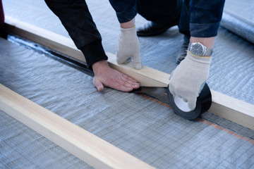 master carpenter mounts pine wood floor - eco-friendly flooring. gluing the insulation layer under...