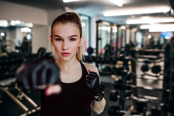 Young girl or woman with gloves, doing exercise in a gym.