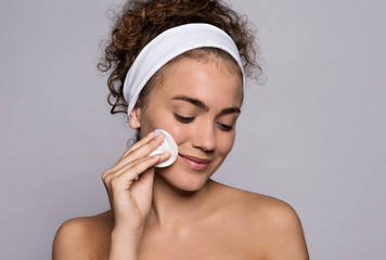 A portrait of a young woman cleaning face in a studio, beauty and skin care.