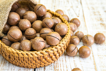 Shelled and unshelled macadamia nuts on wood vintage background