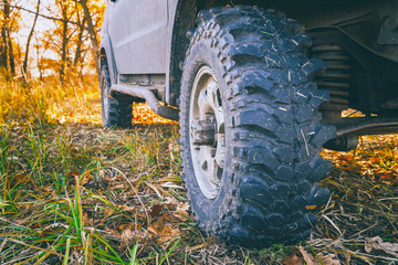 Fototapeta na wymiar Wheels off-road car standing on the grass in the forest. Selective focus