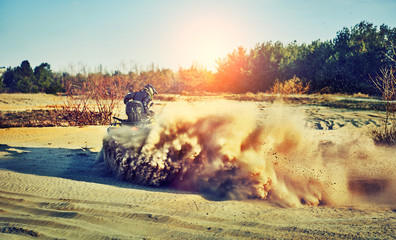 Teen riding ATV in sand dunes making a turn in the sand © 6okean