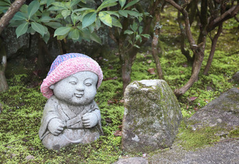 Stone statue of smiling Jizo in a knitted hat, Miyajima, Japan