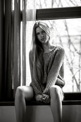 Obraz premium Beautiful long hair girl sitting on window