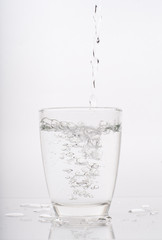 pouring water into a glass isolated on white