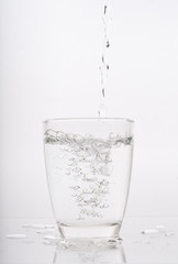 pouring water into a glass isolated on white