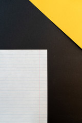 A sheet in a ruler in the lower left corner and a yellow paper triangle in the upper right corner on a black background. Place for text. Close-up. Top view